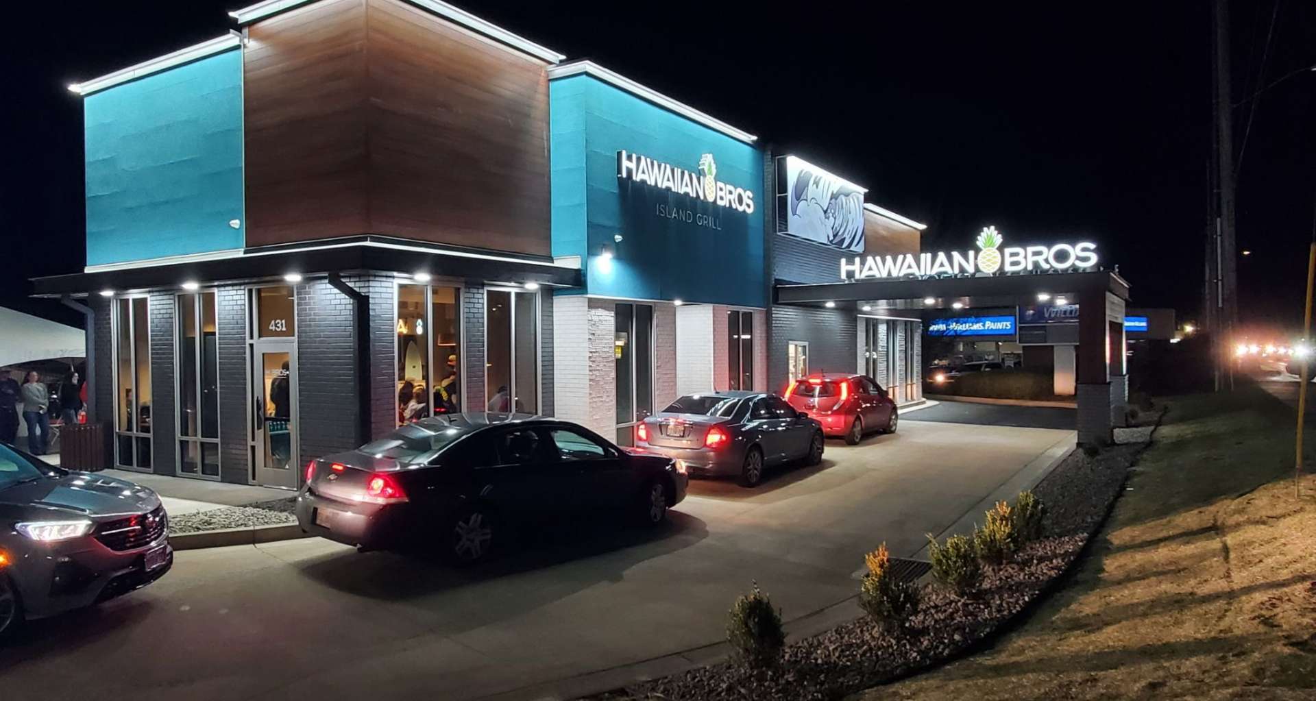 Existing Hawaiian Bros Island Grill restaurant exterior with teal accents, pineapple logo and outdoor seating.