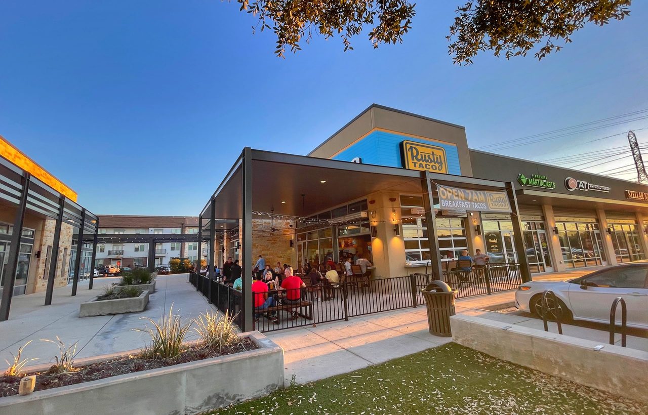 Exterior of an existing Rusty Taco restaurant with its blue-and-yellow storefront and patio